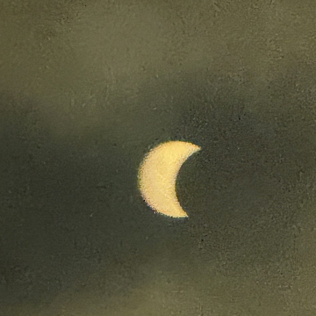 Crescent-shaped partial eclipse seen through evening haze in A Coruña